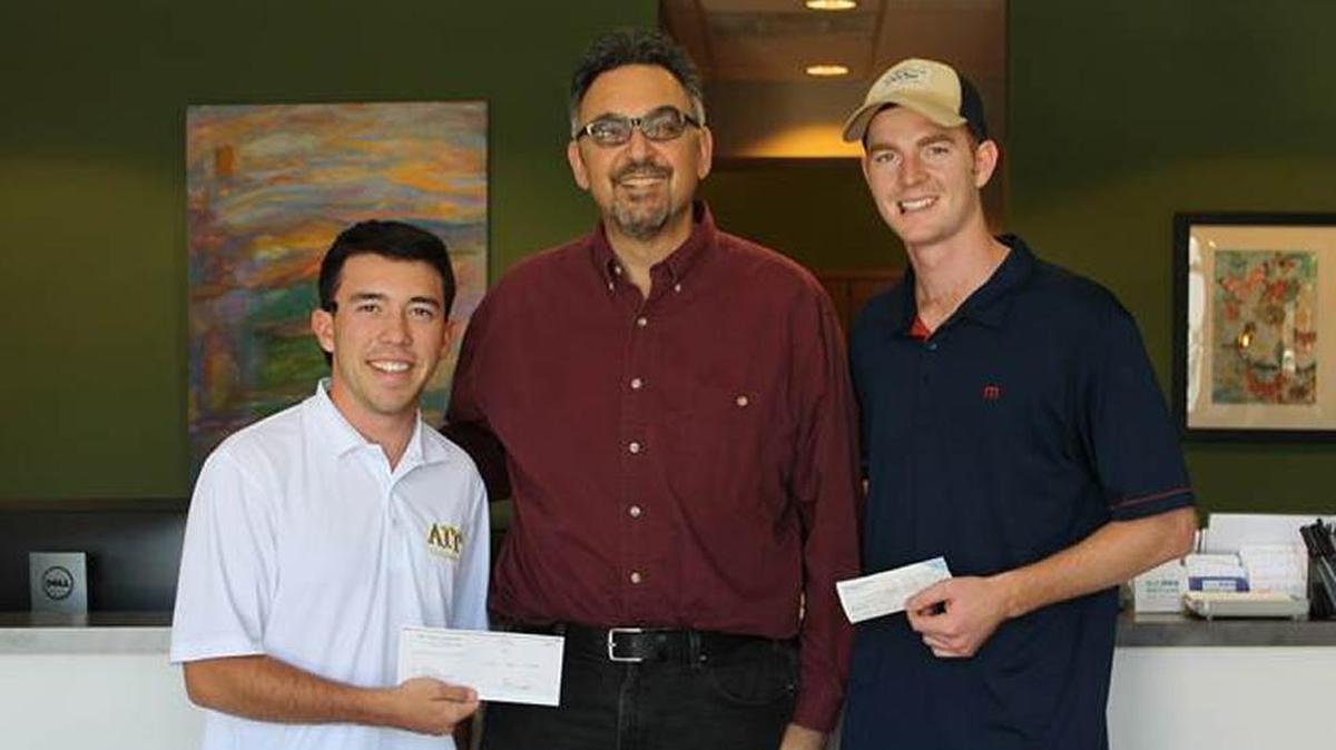 Tanner Hedrick, left, of Alpha Gamma Rho and Chase Broersma, right, of Phi Kappa Psi present checks to Michael Kaplan, fund development manager at Transitions-Mental Health Association. The fraternities held a a night of amateur boxing that raised $5,006.86 for TMHA.
