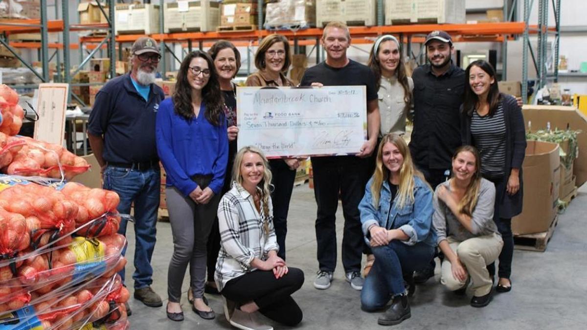 Food Bank Coalition staff receive a check from Mountainbrook Church’s lead pastor Thom O’Leary and creative pastor Karen George in the Food Bank’s warehouse.