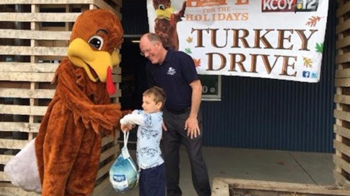 Food Bank CEO Kevin Drabinski, right, stands with Jackson, age 7, who is donating a turkey at the annual Turkey Drive for his fourth year in a row.
