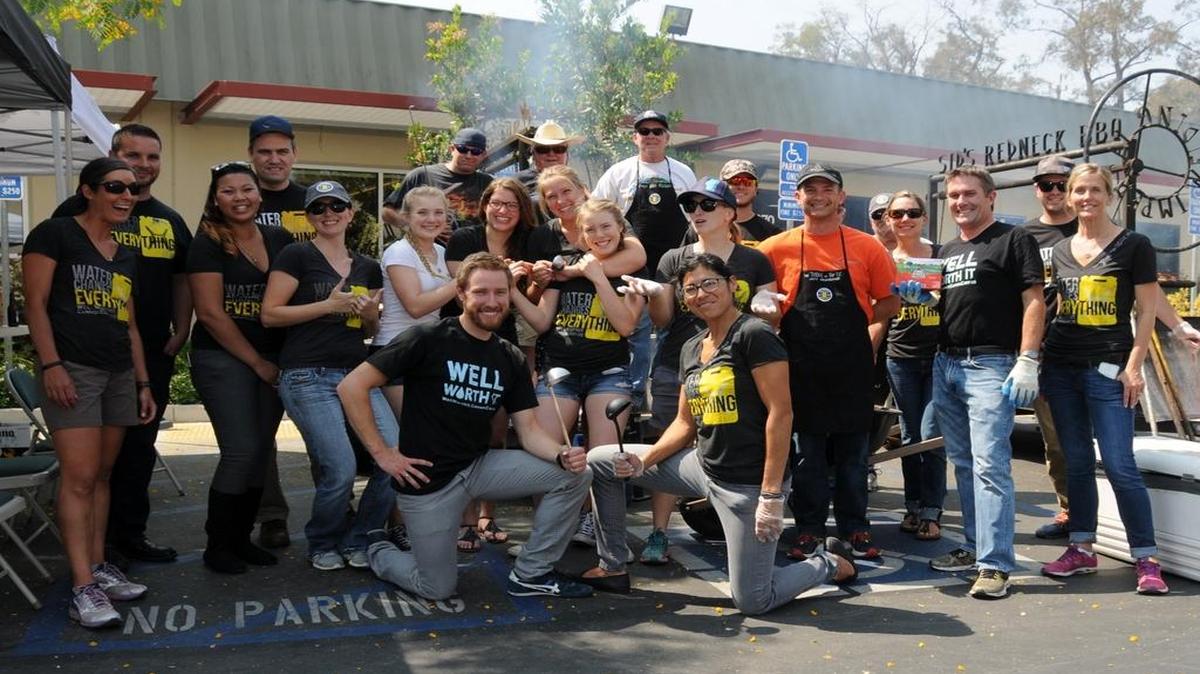 Local engineering firm Cannon Corp. sold out of dinners at its annual Well Worth It drive-thru barbecue fundraiser to benefit families in need and bring clean water to people in developing countries. Cannon employees and volunteers gather around the barbecues for a group photo.