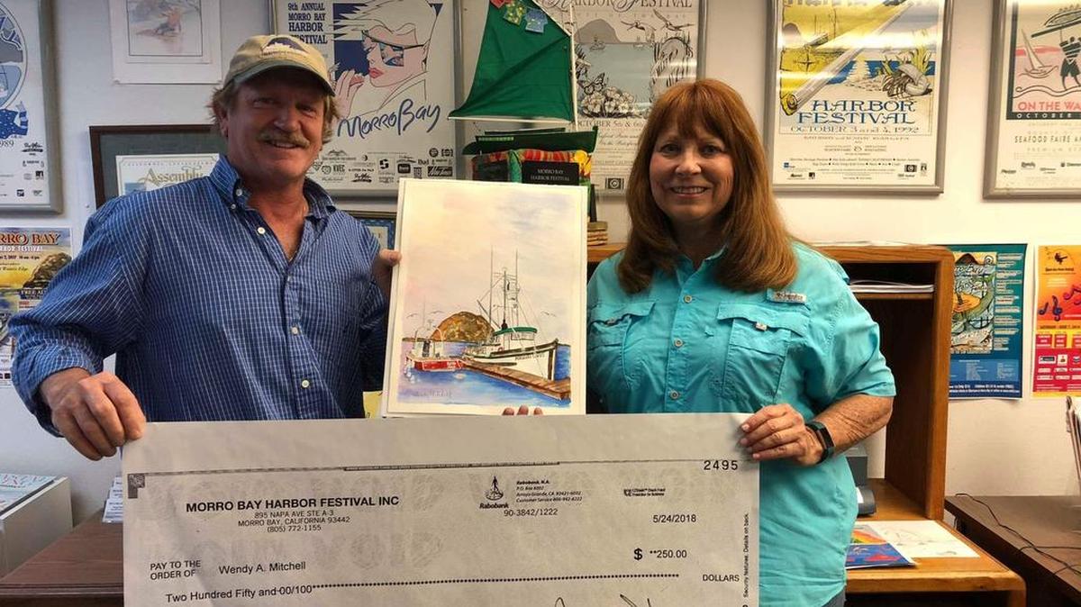 Morro Bay Harbor Festival Board president Jim Sanders and poster art contest winner Wendy Wilkins Mitchell show her painting, along with the $250 check she received for her winning entry.