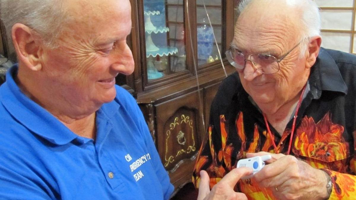 Bob Kelley, left, hands a Freedom Alert medical pendant to the columnist’s husband, Richard Tanner.