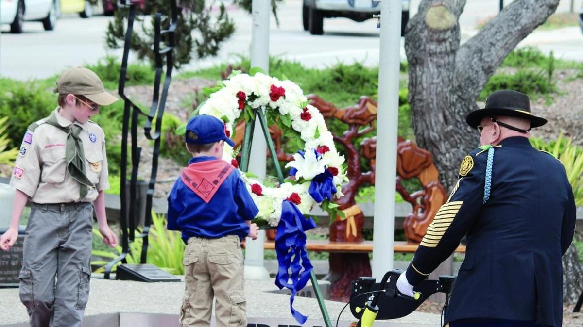 Cub Scout Dillon Riley places a tribute wreath on the memorial as veteran Alan Doctor, right, looks on Monday during 2015 Memorial Day ceremonies in Cambria.