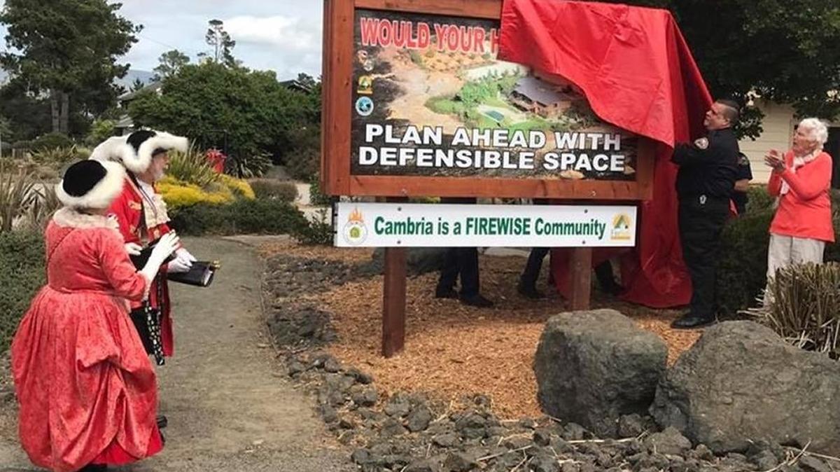 Cambria’s Bev and Jerry Praver, San Luis Obispo County town criers, stand by while as a Firewise Community sign is unveiled in front of the fire station this spring.