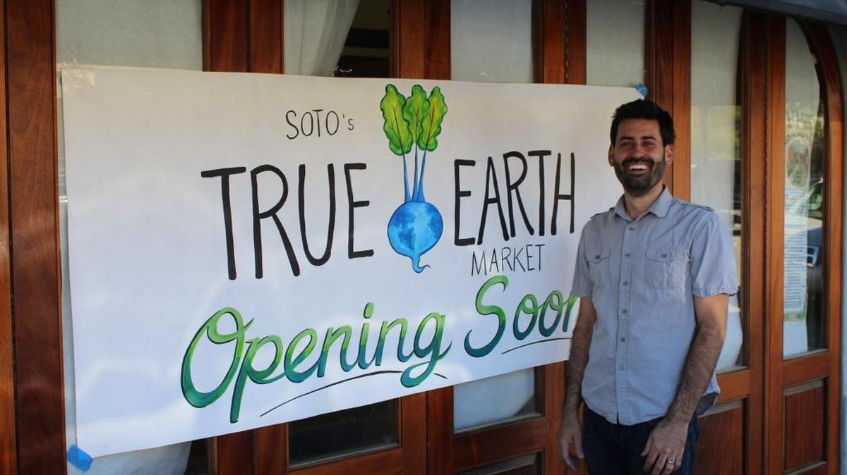 Andre Ponce shows off the newly refinished doors on the front of Soto’s True Earth Market on Monday.