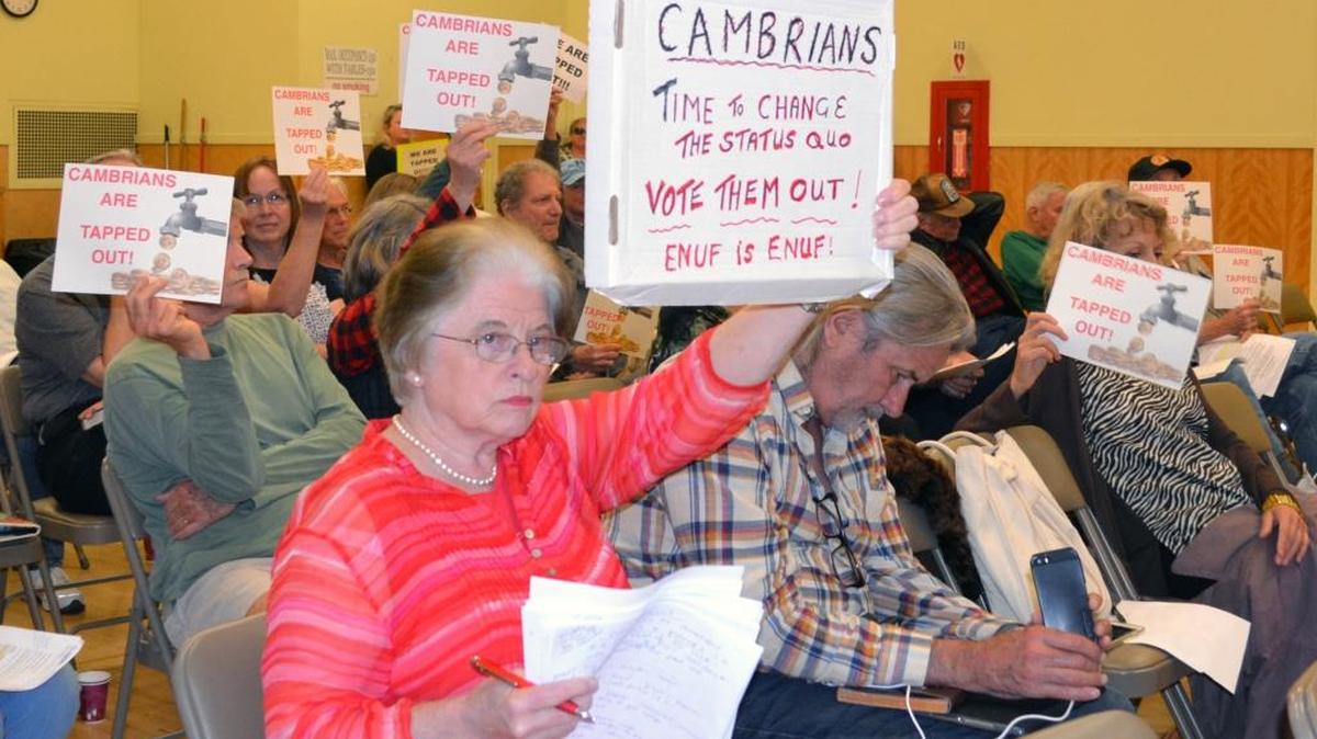 Tina Dickason and other audience members hold signs protesting Cambria CSD spending and other policies at the May 26 board meeting.