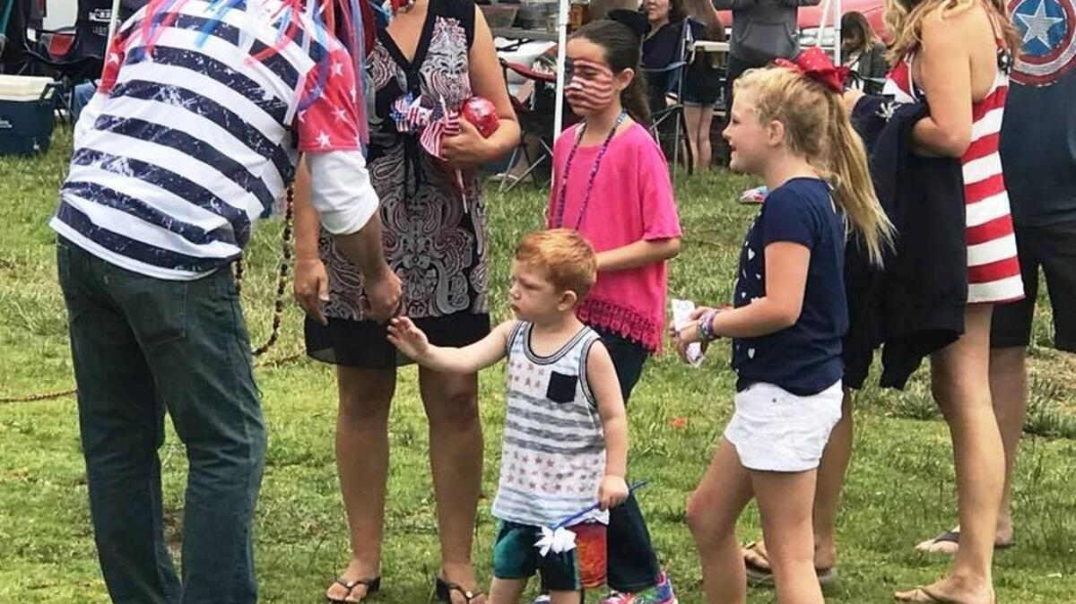 Michael Shanley, dressed in a red, white and blue hat and sunglasses tinted like the American flag, hands out prizes to children following the kids competition at Shamel Park early Tuesday afternoon, July 4.