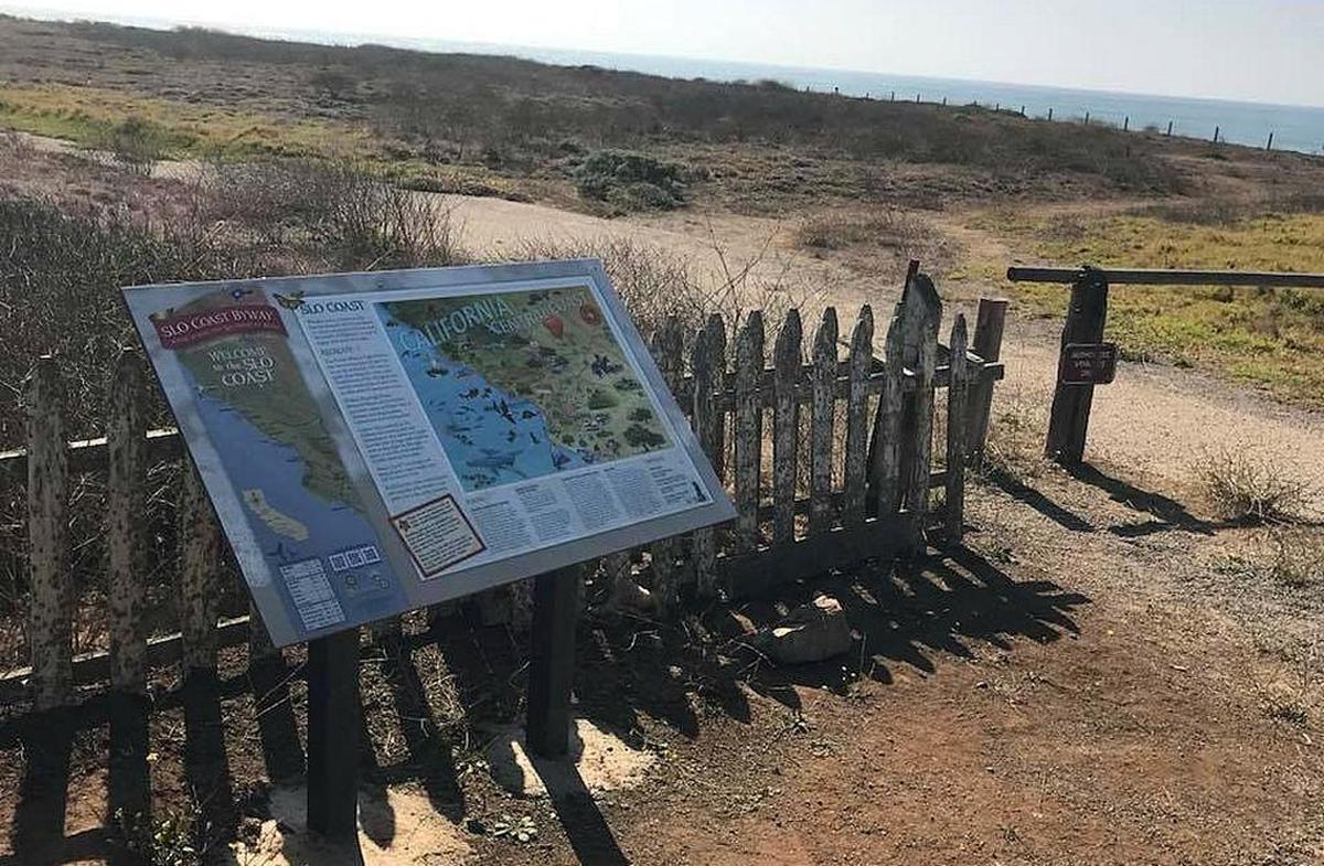 A sign marks the coastal trail at the south end of the Piedras Blancas Motel parking lot.