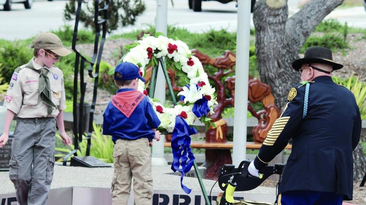 Cub Scout Dillon Riley places a tribute wreath on the memorial as veteran Alan Doctor looks on Monday during Memorial Day ceremonies in Cambria.
