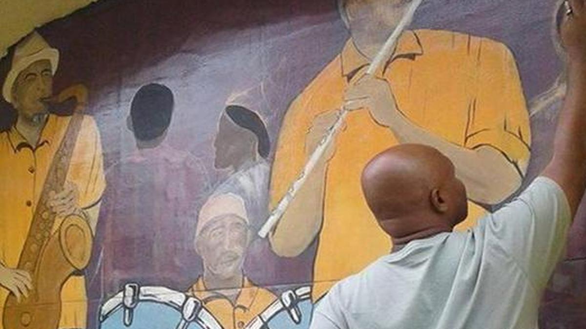 Lucien Downes, an artist friend of the columnist’s living in the Virgin Islands, adds vibrant “island life” art to an outdoor wall that was torn apart by Irma’s winds.