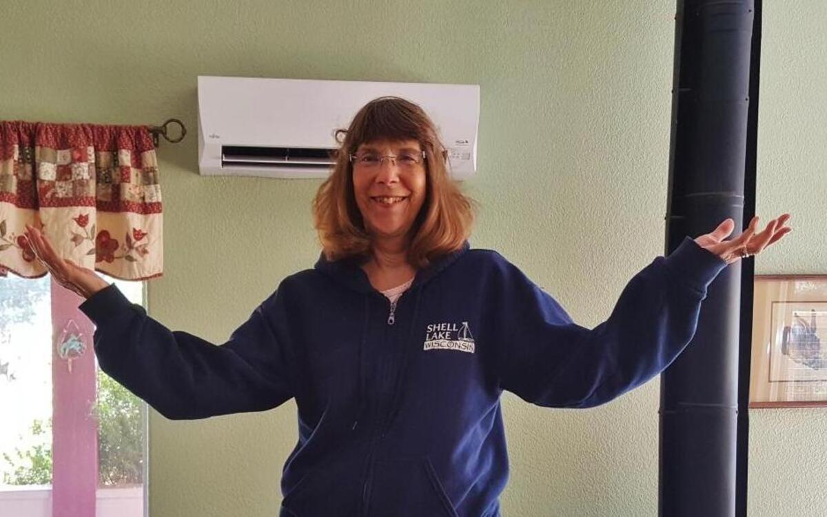 Marcia Rhoades in front of her 115-volt, ductless air-conditioning system.