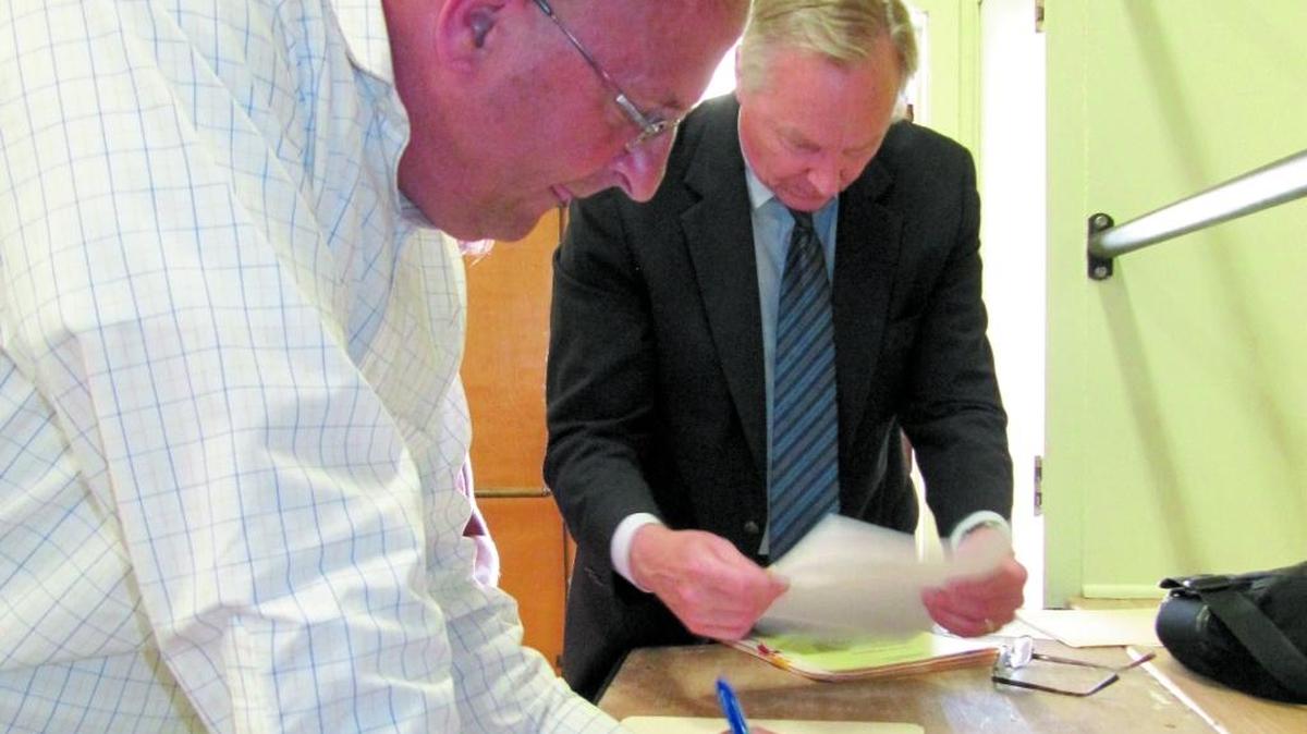 Jerry Gruber, left, general manager of the Cambria Community Services District, signs loan papers in August 2014 at the Veterans Memorial Building with Charles Adams, the district’s bond counsel from the Jones Hall legal firm in San Francisco.
