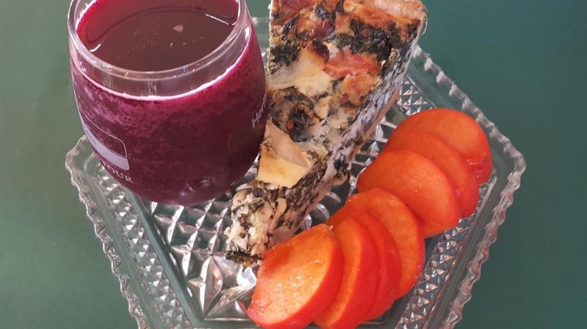 A healthy wedge of quiche Florentine is served with healthful Fuyu persimmons and fresh pomegranate juice.