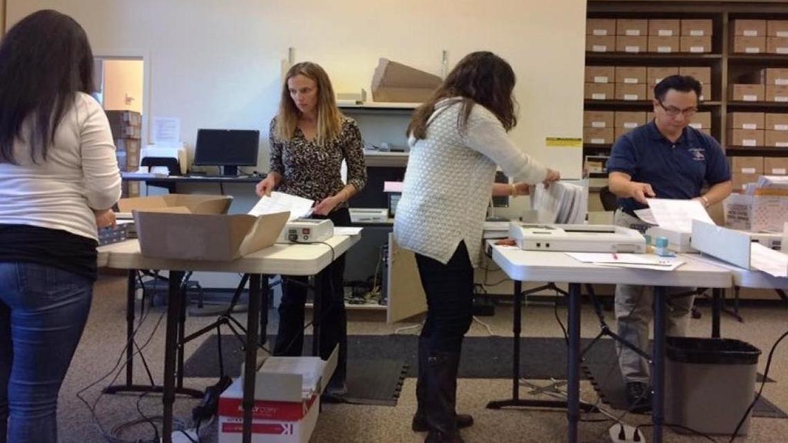 Tommy Gong, San Luis Obispo County clerk-recorder, right, joins in the process of feeding ballots into counting machines.