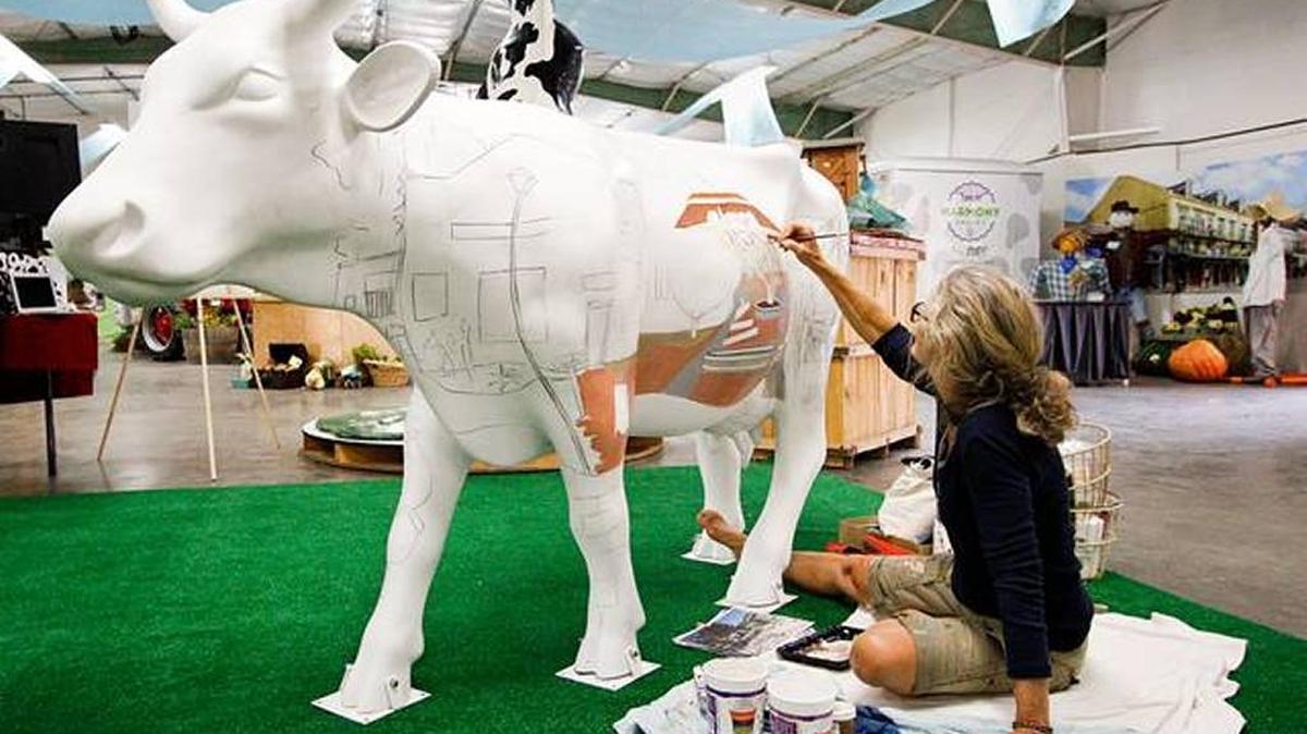 Artist Carol Paulsen paints a scene of Harmony on a fiberglass cow on July 22. The CowParade public art demonstration at last year’s California Mid-State Fair was a prelude to the countywide display set to begin in September.