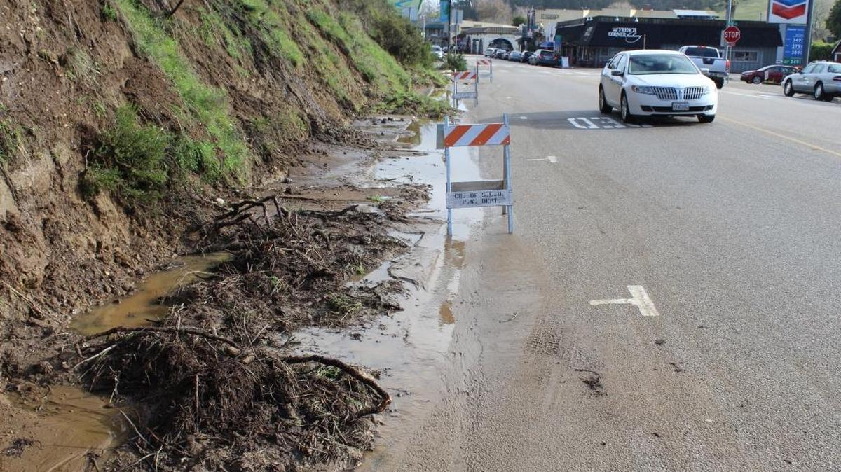 A car passes by a section of hillside that slid down onto the edge of the roadway on Main Street in Cambria’s East Village earlier this month.
