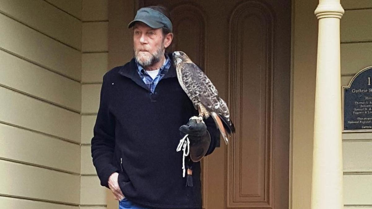 Terry Cook, educational ambassador for Pacific Wildlife Care, welcomes kindergarteners to the Historical Museum with Buddy, the red-tailed hawk.