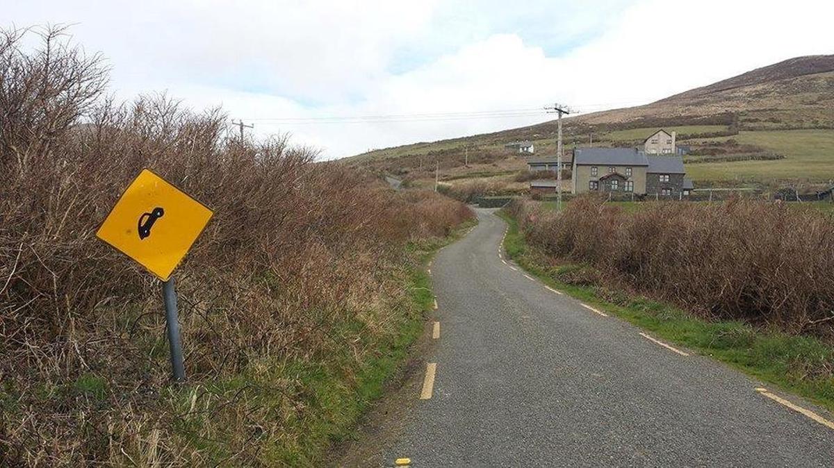 The shortcut not taken on the Dingle Peninsula in Ireland. Note the sign depicting the steep grade, with the car at a severe angle.