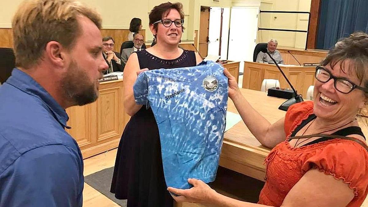 Dianne Brooke, right, receives an honorary Water Department T-shirt from Cambria Community Services District board President Amanda Rice, as Water Supervisor Jason Buhl looks on.