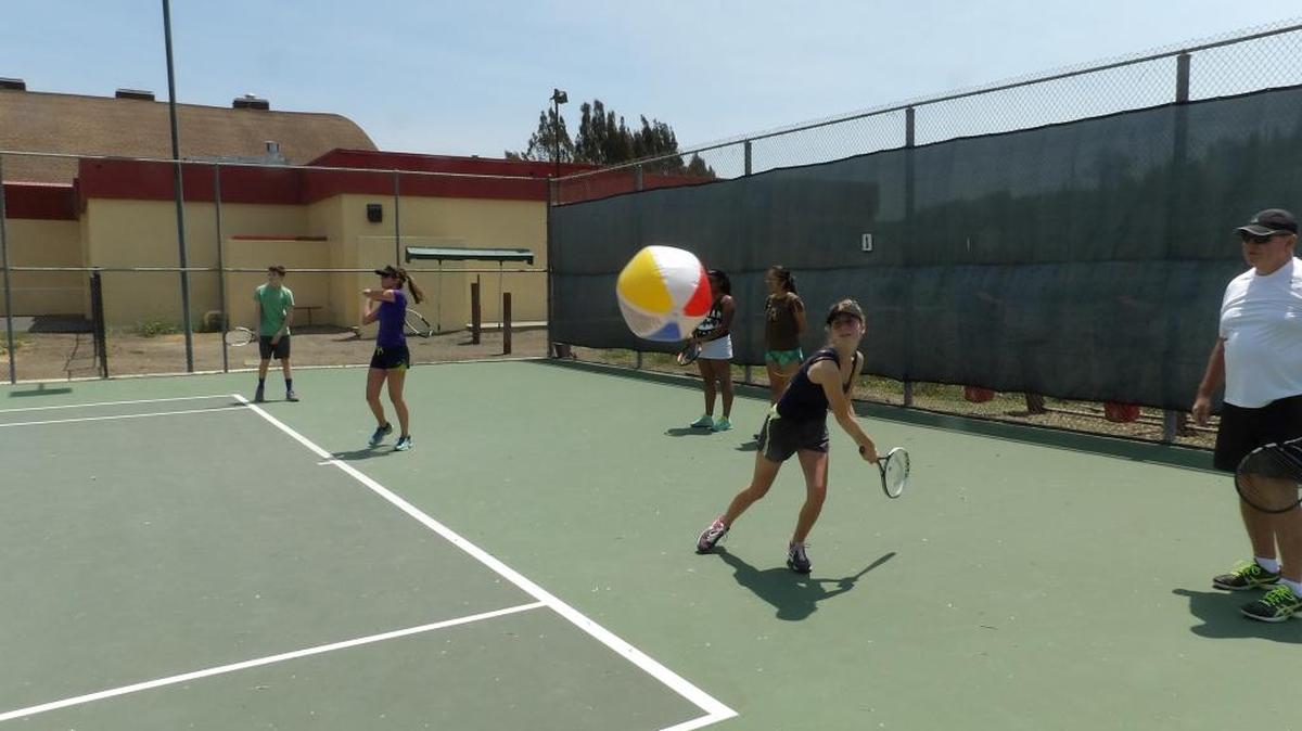 Varsity tennis player Savannah Lyon, a senior, prepares to hit the beach ball during topspin practice at Coast Union on July 27. Coach Tom Coxwell is at right.