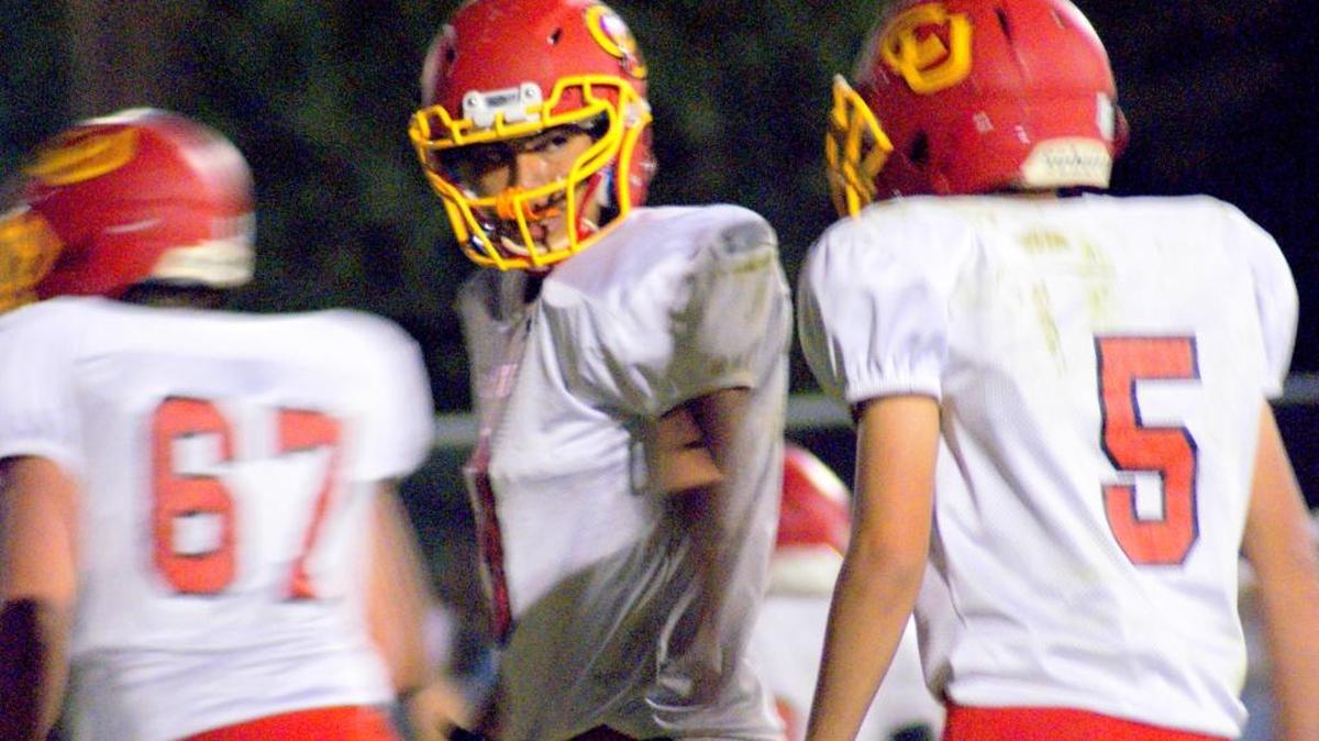 Quarterback Riley Kennedy, center, shares last-minute instructions with Juan Meja (5) prior to an offensive play Friday night, Sept. 30, at Cuyama Valley. Also pictured: lineman Nic Robertson (67).