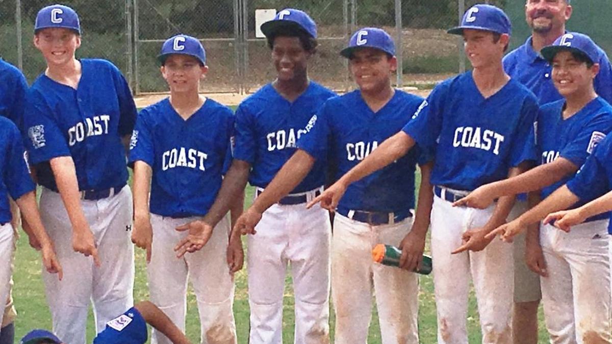 Cambria Reds players (Emi Pena holding water bottle; Anhase Martin to Pena’s right), along with other members of the Coast Intermediate All-Stars, joyfully point at Reds player Michael Sison on the ground. Sison’s walk-off hit won a state tournament game 12-11 for Coast on Saturday, July 8.