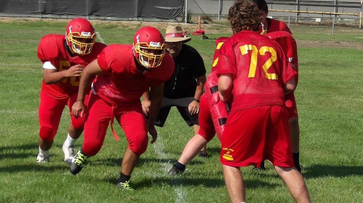 Head football coach Ron Garcia, in black, teaches blocking strategies during an Aug. 10 practice session at Coast Union High School. The lead blocker is Andres Quintero, and the trail blocker is Luis Aguilar; No. 72 is Nik Robertson.
