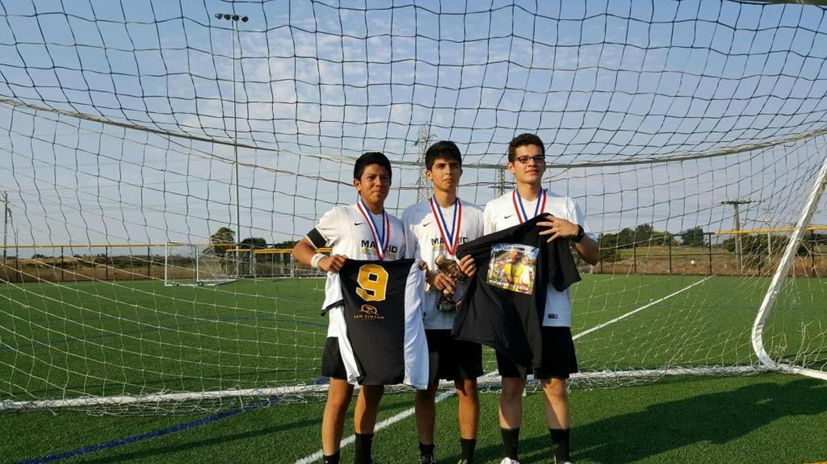 After Dante Garcia’s soccer team, Madrid Premier, won gold in their Division 3 bracket at the Stanford Summer Classic Tournament, three of his teammates — from left, Daniel Pena, holding Dante’s jersey; Fidel Figueroa Jr., holding the trophy; and Leo Martinez, holding a jersey with a photo of Dante kissing a trophy from a previous championship — said they knew Dante helped them win.