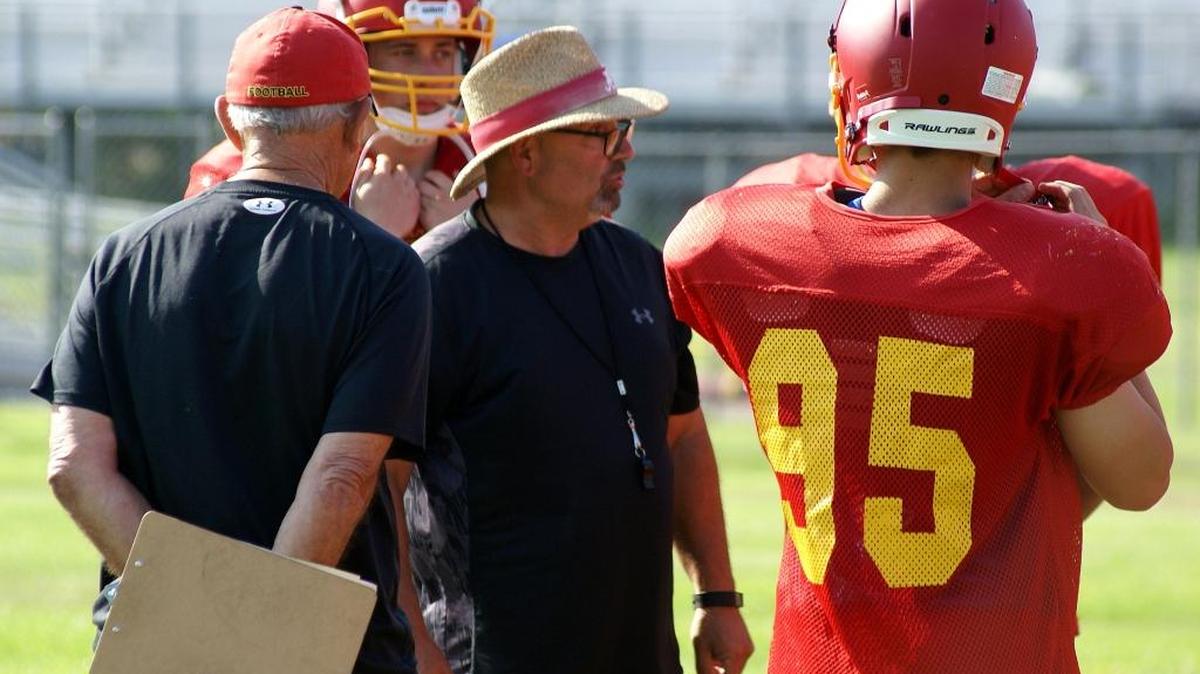 Head coach Ron Garcia, center, and assistant Charlie Casale, left, work with members of the Coast Union football team during preseason workouts in late August.