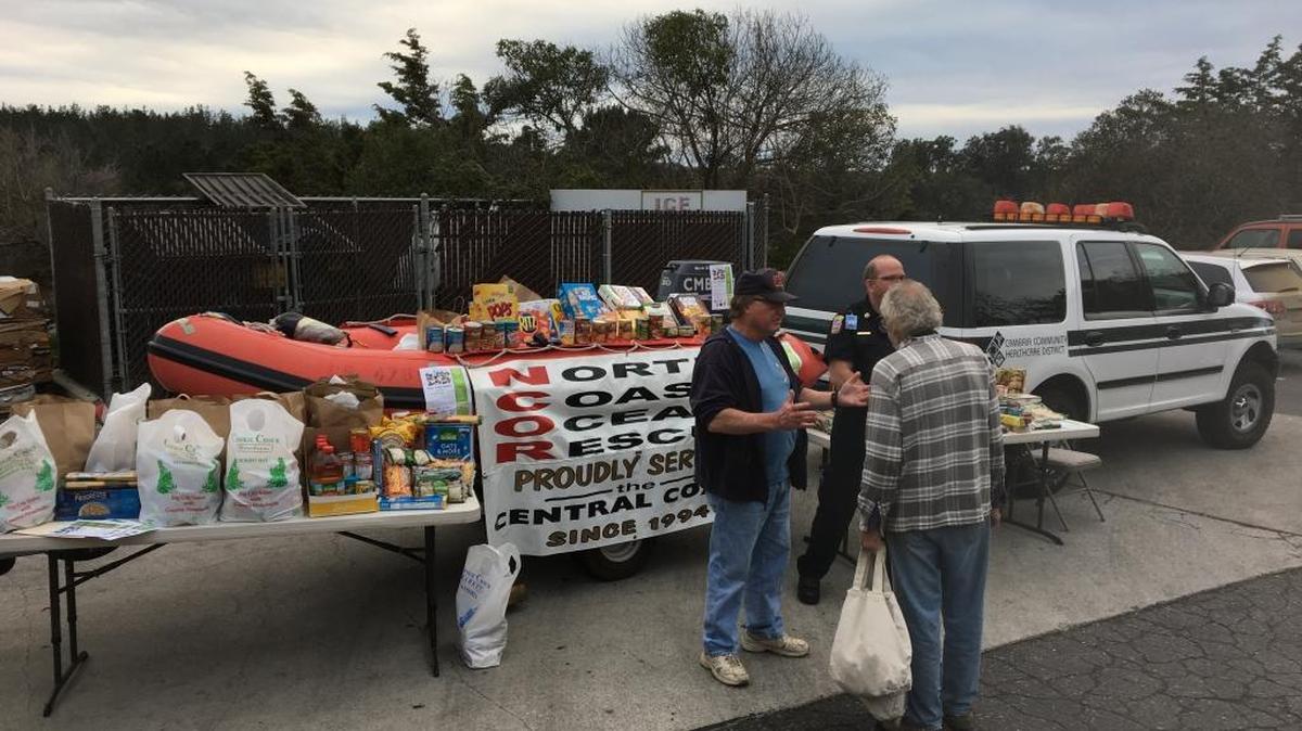 Cambria Community Healthcare District Trustee Jerry Wood discusses the food drive with donor Harry Farmer as CCHD paramedic Tim Denes looks on.