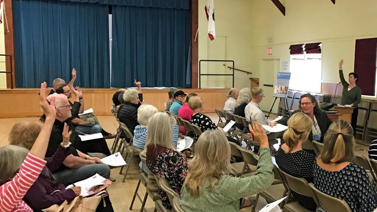 Audience members raise their hands in response to a question from Linda Beck of Square One Elder and Health Advocacy, who asked how many of them already have advanced health-care directives. Beck spoke during a meeting Thursday, Nov. 9, at the Cambria Veterans Memorial Building.