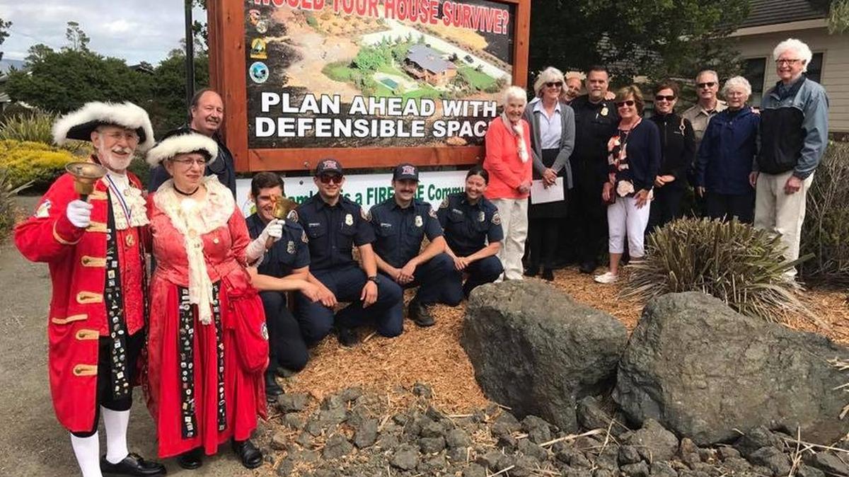 San Luis Obispo County’s official town criers, Bev and Jerry Praver, left, join members of Cambria’s FireSafe Focus Group, the Cambria Fire Department and other dignitaries to unveil a sign at the fire station announcing Cambria’s status as a Firewise Community. The designation came about through the efforts of the focus group in developing an action plan that promotes fire safety.