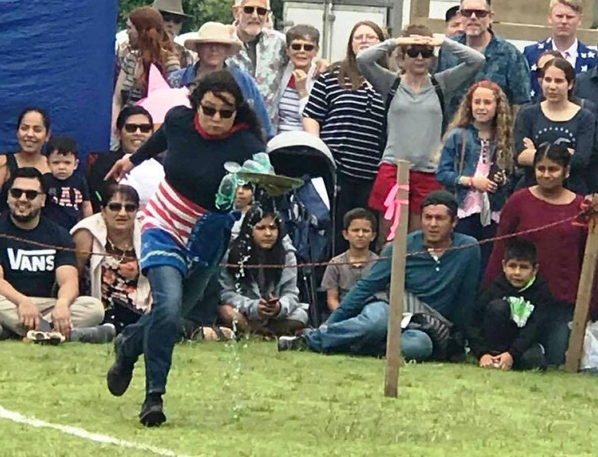 Muriel Boerboom tries in vain to maintain control of three filled glasses as she competes in the for Centrally Grown in the Fourth of July waiters race at Cambria’s Shamel Park in 2017.