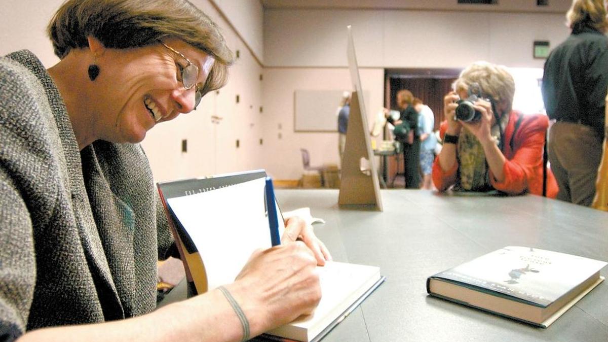 Catherine Ryan Hyde smiles as a fan takes her picture during a book signing at the San Luis Obispo County Library.