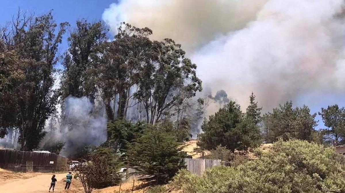 Two people watch smoke rise from just off Main Street in Cambria during a fire that burned nearly 4 acres in the East Village and forced evacuations on Wall Street and Bridge Street.
