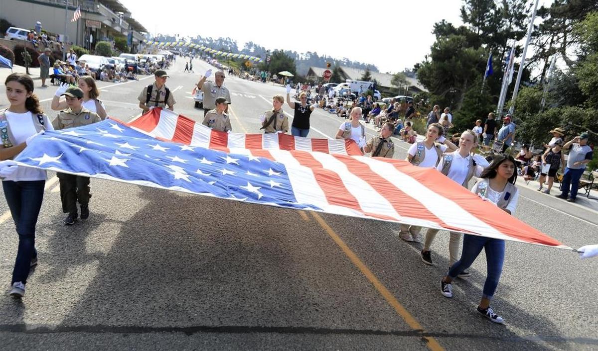 Cambria Girl and Boy Scouts and 4H kids walk with a large American flag during last year’s Pinedorado Parade.