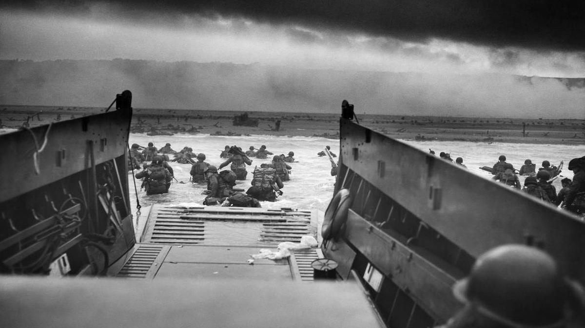 An LCVP (Landing Craft, Vehicle, Personnel) — also known as a Higgins boat — from the U.S. Coast Guard-manned USS Samuel Chase disembarks troops from Company E, 16th Infantry, 1st Infantry Division (the Big Red One), wading onto the Fox Green section of Omaha Beach (Calvados, Basse-Normandie, France) on the morning of June 6, 1944. American soldiers encountered the newly formed German 352nd Division when landing. Two-thirds of Company E were killed during the initial landing.