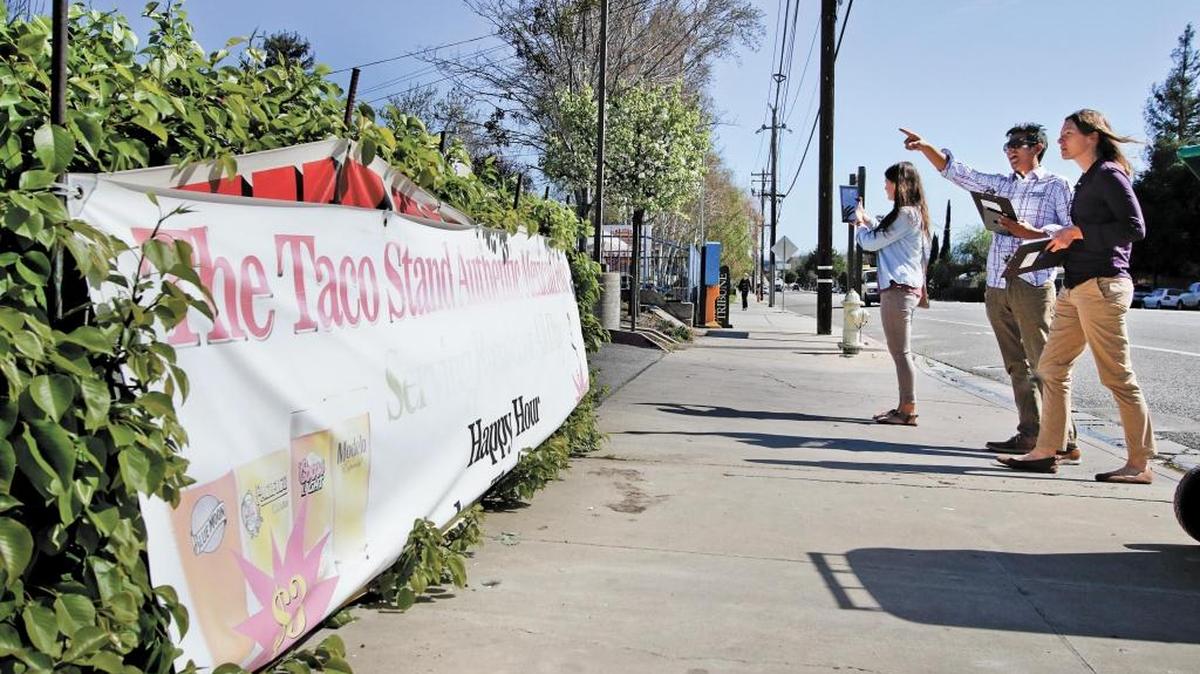During a tour in March 2015, Katie Banister, right, Alfredo Castillo and Sarah Wood from the Atascadero planning department discuss signs that are in violation of the city ordinance like this banner, left, on El Camino Real. The trio were out contacting businesses with temporary signage that was in violation in hopes of helping bring them into compliance.