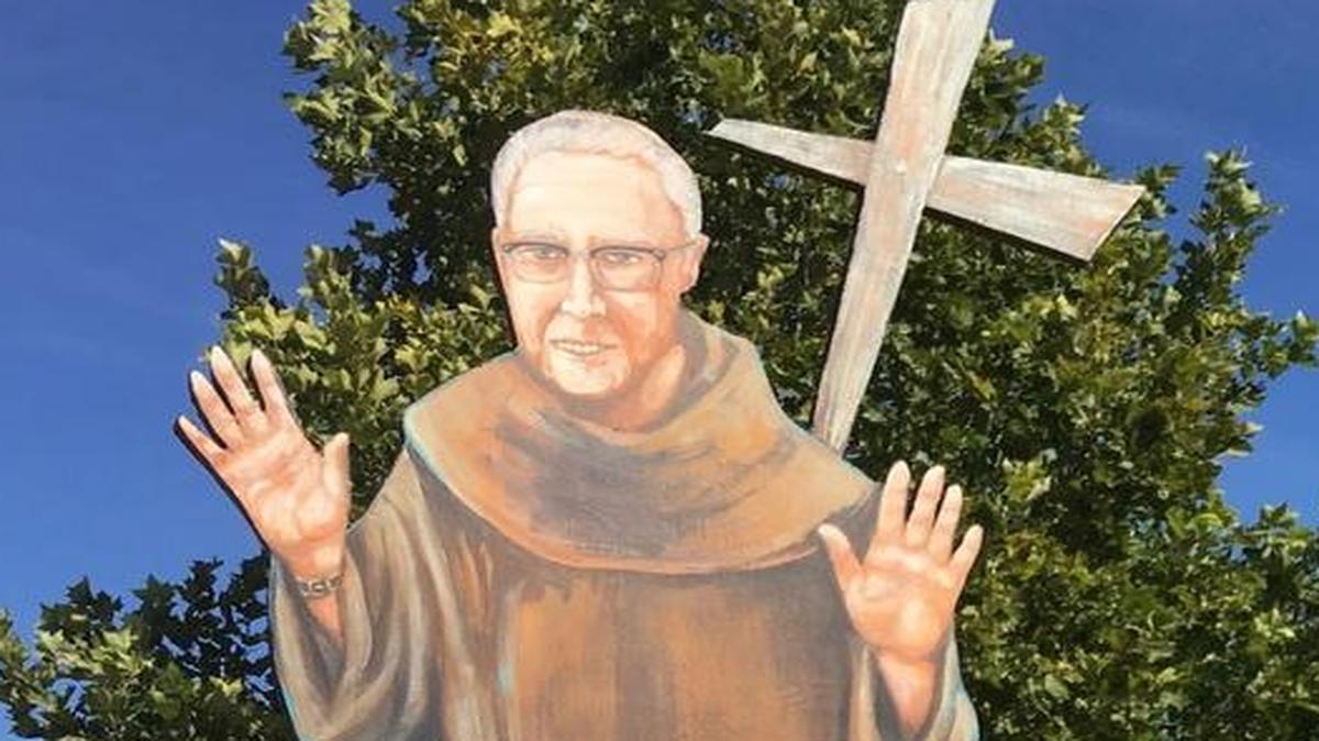 Artist Steve Kalar stands next to a life-size image of Father Reginald McDonough OFM in San Miguel.