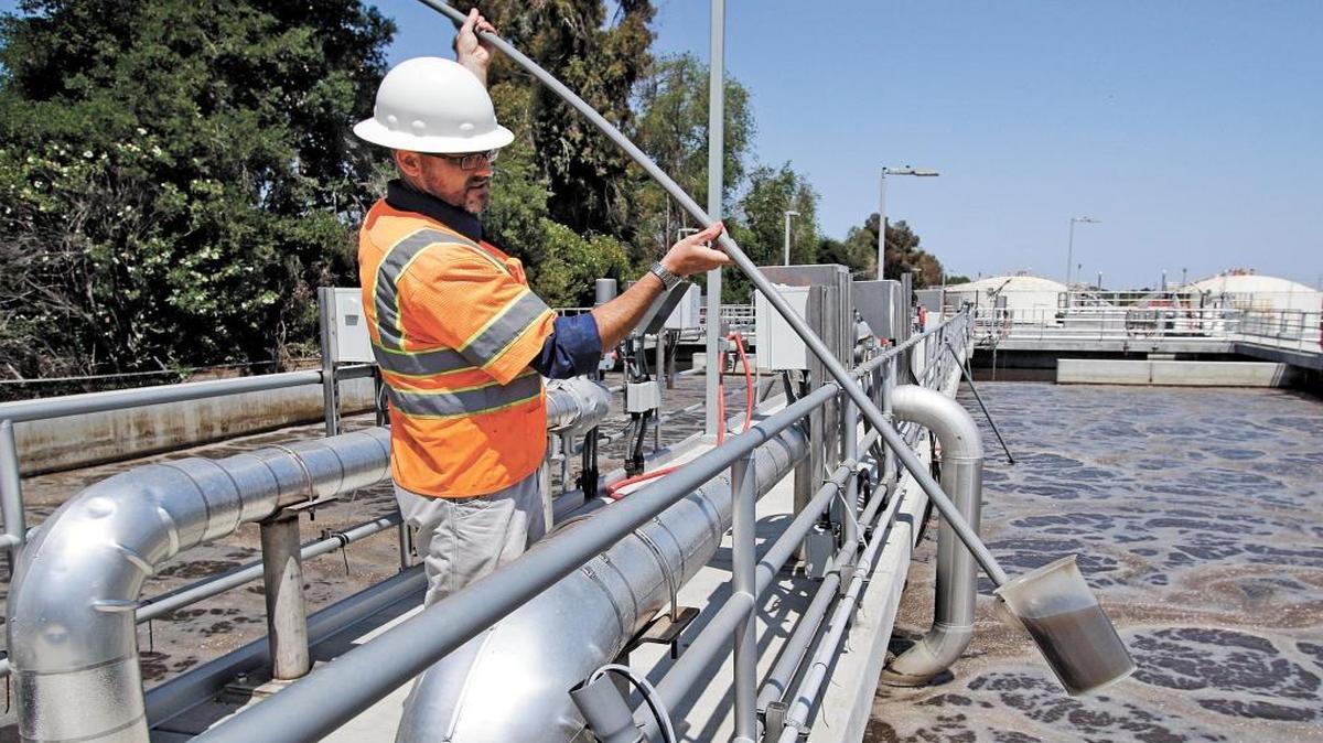 Wastewater manager Matt Thompson grabs a sample of water from the middle of the treatment process at the Paso Robles sewage treatment plant in May 2015.