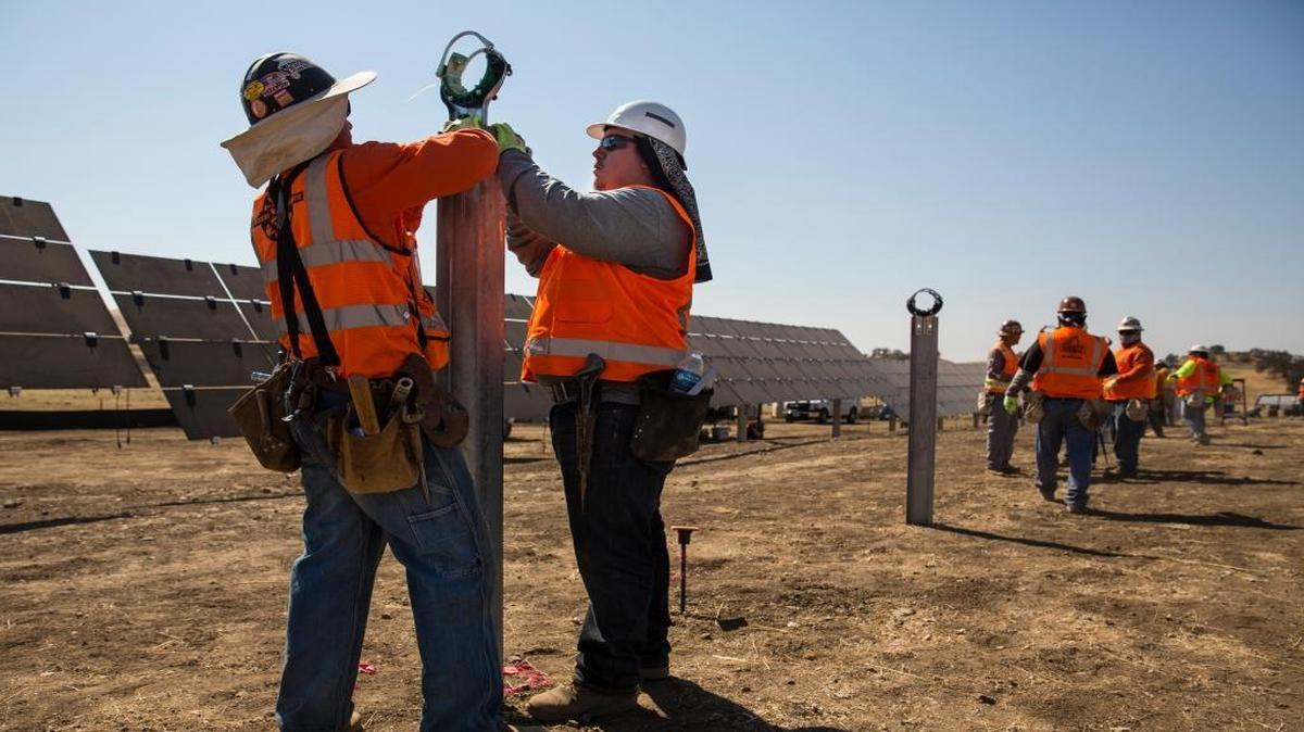 Workers install rotator hinges at First Solar’s energy plant near Cholame on Aug. 18.