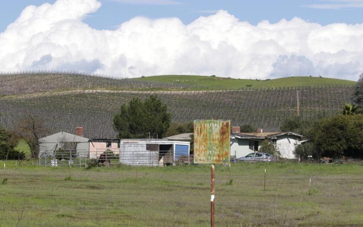 A dilapidated green sign marks the eastern boundary of Our Town, a project in the 1960s that proposed to bring 4,000 homes to the east side of Paso Robles off Linne Road. The homes in the background are among the 13 models built by developer Winfield Scott Condict. He eventually went bankrupt.