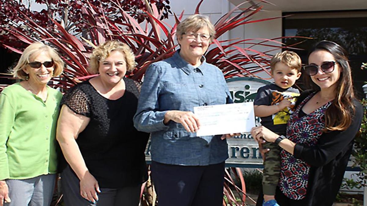 Val Barboza, Cal Poly Women’s Club co-president, and Tonya Iversen, director of ASI Children’s Center, stand with Chris Hoover, Cal Poly Women’s Club co-president, and she presents a check to Lisa Lemos Jensen.