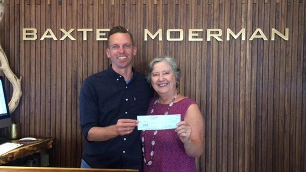 Matt Baxter, left, co-owner of Baxter Moerman, presents a donation to CASA grants manager Susan Graves.