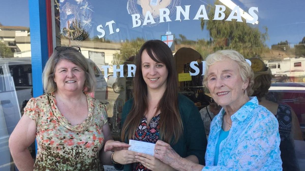 Saint Barnabas Thrift Shop volunteers Sherry Richison, left, and Shirley Holgate, right, present a check for $1,000 to Bryn Smith of Community Action Partnership of SLO County.