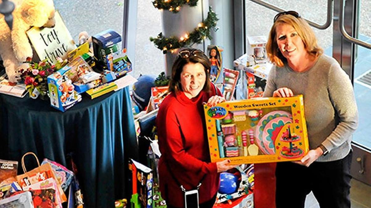Sharon D. Armstrong, wife of Cal Poly President Jeffrey D. Armstrong, left, and Penny Bennett, associate dean for student success in the College of Liberal Arts, show one of the donated toys at the holiday party.