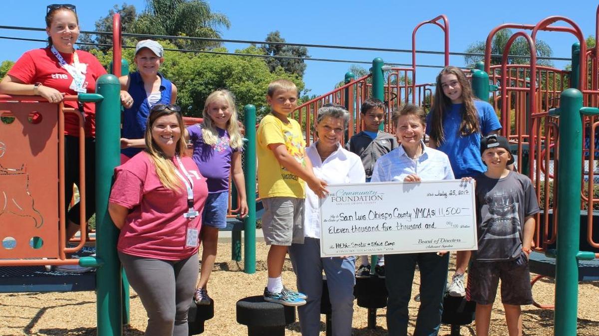 From left, Merial Buikema, YMCA Hawthorne Camp assistant director; Jennifer Kreps, YMCA director of Youth Development and Grant-Funded Programs; Heidi McPherson, CEO of The Community Foundation San Luis Obispo County; Monica Grant, CEO for SLO County YMCA; and Hawthorne Trailblazer YMCA Summer Camp participants celebrate the recent grants to the YMCA.