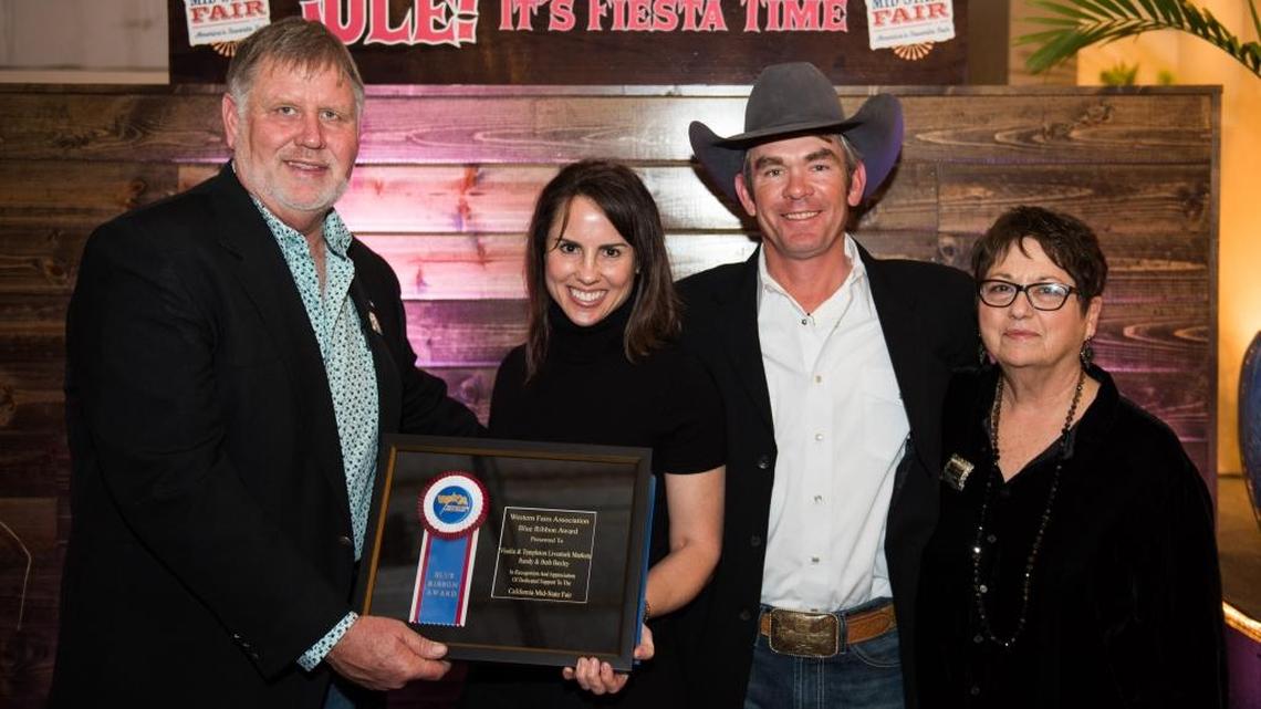 California Mid-State Fair Board President Chris Darway, left, presents the Western Fairs Association Blue Ribbon Award for Service to Beth Baxley and Randy Baxley, while CMSF Board Vice President Dee Lacey, right, looks on.