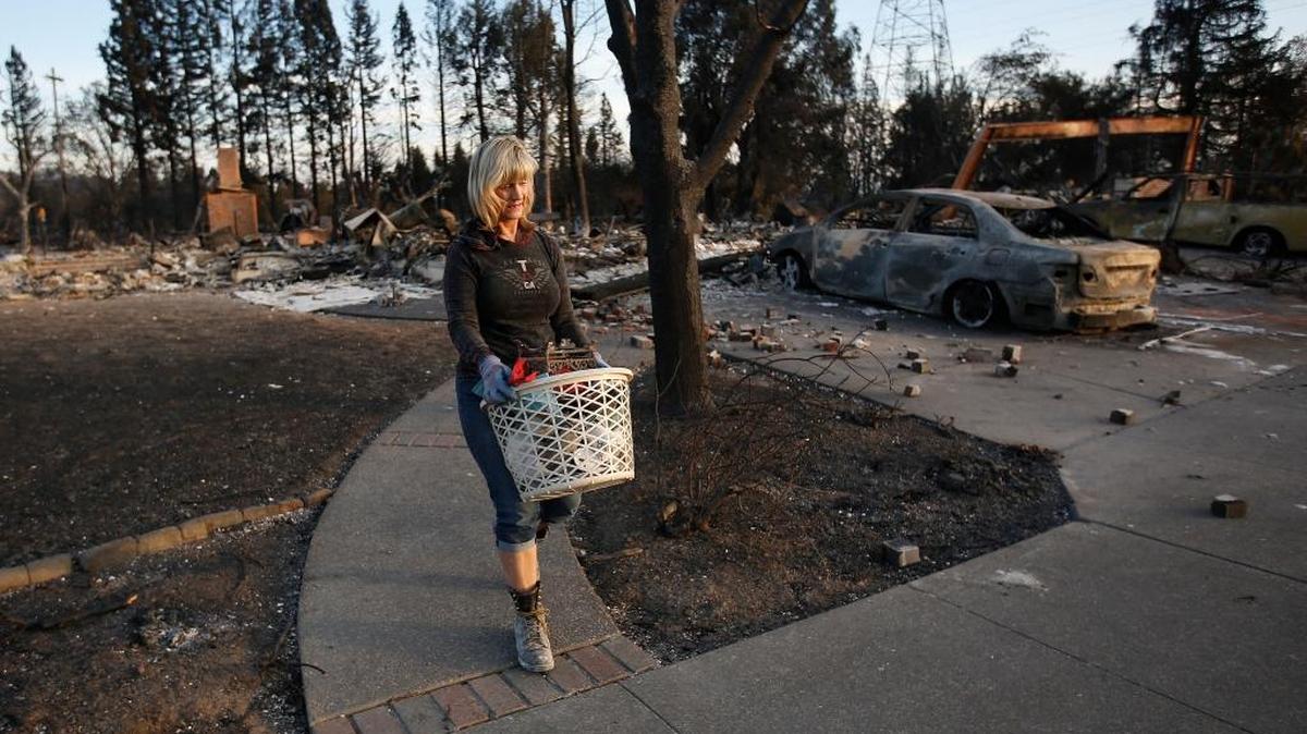 Debbie Wolfe uses a laundry basket to carry a few items she found in her burned home in Santa Rosa on Oct. 17. 2017. SLO County groups have donated funds and items to help the victims of the wildfires. They continue to accept donations.