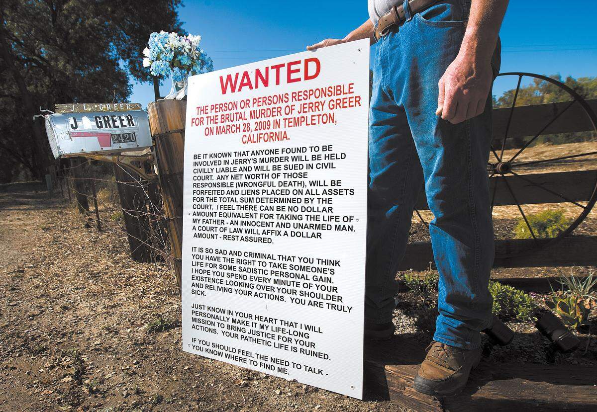 Brian Greer holds a wanted sign he made for the person who killed his father, Jerry Greer, in 2009. The elder Greer was shot to death while sleeping in his Templeton home and the case is still unsolved. Brian Greer was named a person of interest in the case in August.